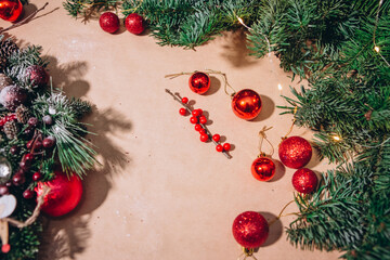 Fototapeta na wymiar Red Christmas balls, fir branches, a garland with bulbs lie on the table