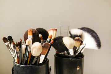 Various makeup brushes on gray background