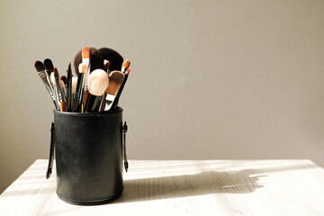 Make up brushes in black box on light background with shadow. Place for text.