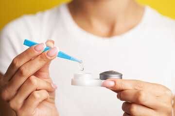Close up of woman get contact lenses out of container with liquid