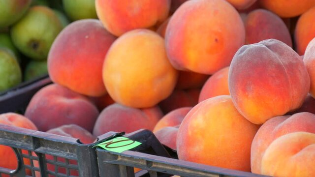 Close up view of ripe beautiful large fresh pink peaches fruits on a street market counter or a vegetable store in summer