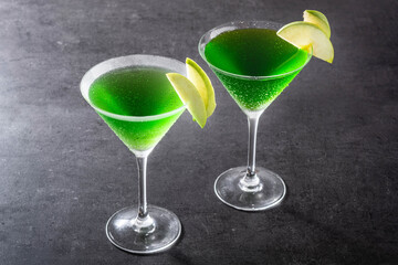 Green appletini cocktail in glass on black background. Copy space