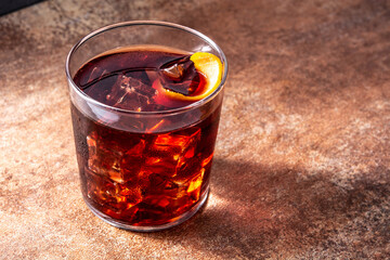 Boulevardier cocktail and orange zest on rusty background.Copy space