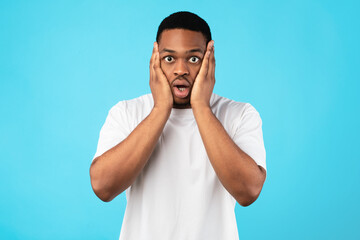 Naklejka premium Overwhelmed Black Man Cupping Face Looking At Camera, Studio Shot