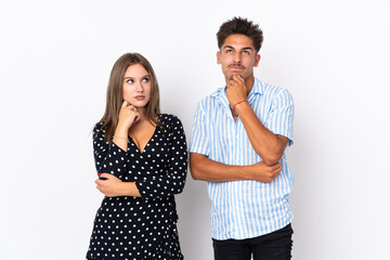 Young caucasian couple isolated on white background standing and thinking an idea