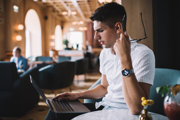 Confused man using laptop in cafe