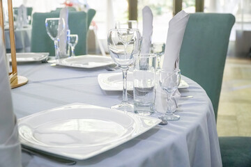 The table in the restaurant is served for lunch. On a table with a white tablecloth, empty wine glasses, a plate, napkins. Selective focus