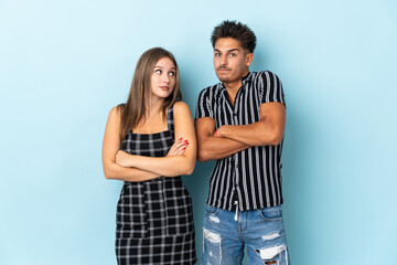 Naklejka premium Teenager caucasian couple isolated on blue background making doubts gesture while lifting the shoulders