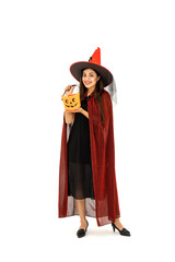 Asian woman wearing Halloween costume as witch in red cloak, on white background, holding orange candy pumpkin bucket for trick or treat, looking at camera