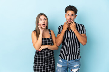 Teenager caucasian couple isolated on blue background surprised and shocked while looking right