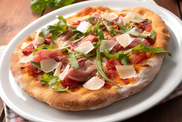 Deliziosa pizza con prosciutto crudo di Parma, rucola e scaglie di formaggio grana, Cucina Italiana