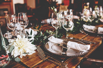 Wedding banquet, serving wooden table with silver plates and decorated with flowers