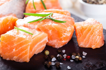 Fresh raw salmon fillet on black cutting board with lemon and spices. Healthy food concept. Close up view