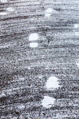 Traces of snow on paving slabs cleared of snow. tracks of snow on asphalt, the first snow, city. Footprint of shoes on concrete tiles city of November. There are many footprints on road.