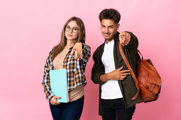 Young student couple isolated on white background points finger at you with a confident expression