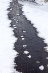 Traces of snow on paving slabs cleared of snow. tracks of snow on asphalt, the first snow, city. Footprint of shoes on concrete tiles city of November. There are many footprints on road.