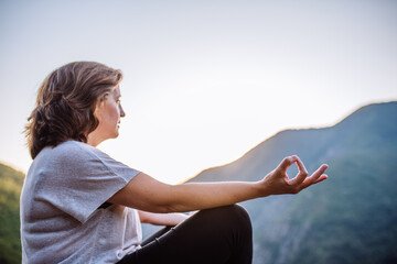 woman doing yoga overlooking the mountain at sunset