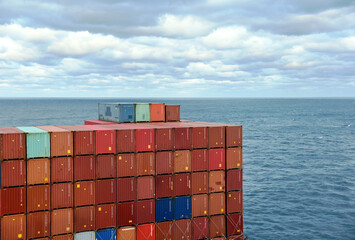 Fully loaded container ship sailing through a blue, calm ocean. View on the stack of the containers...