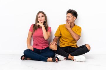 Fototapeta na wymiar Young couple sitting on the floor isolated on white background happy and smiling