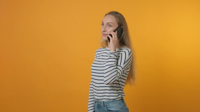 Beautiful young woman talking on a cell phone. Freelance work. Yellow background. 4K video.
