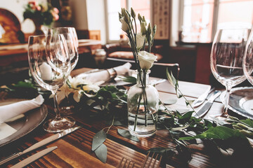 Wedding banquet, serving wooden table with silver plates and decorated with flowers