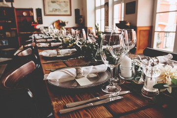 Wedding banquet, serving wooden table with silver plates and decorated with flowers