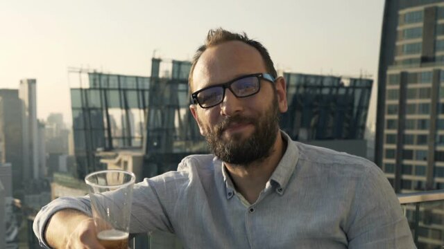 Portrait of happy man drinking cocktail sitting at luxury rooftop bar