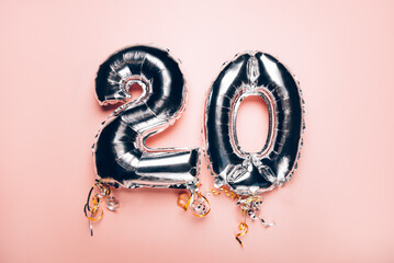 Silver Number Balloons 20 on pink background. Holiday Party Decoration or postcard concept with top view on pink background