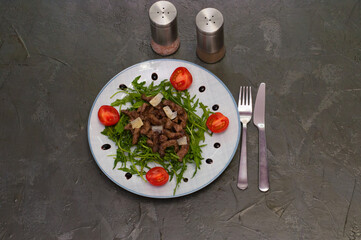 Tasty and juicy grilled meat arugula, cheese, tomato sauce and spices on a dark gray concrete background, top view