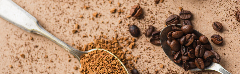 top view of instant coffee and beans in spoons on beige surface, panoramic shot