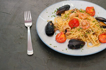 Spaghetti pasta with shrimp, mussels, tomatoes and cheese, copy space. Very tasty and high-calorie, traditional Italian food