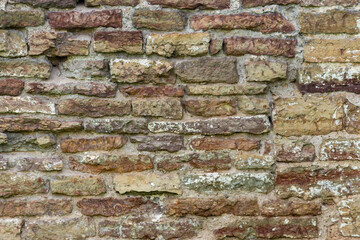 The surface of an old stone wall, masonry of uneven wild hewn stones.