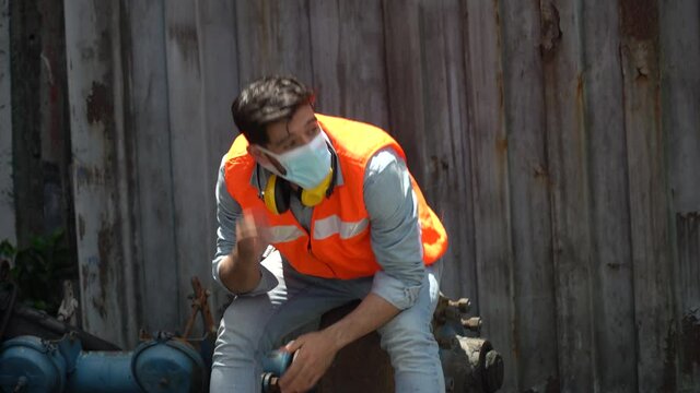 furious young worker about to throw and break helmet and face mask at workplace. engineer unemployment during corona virus pandemic . factory shutdown by covid 19 outbreak .