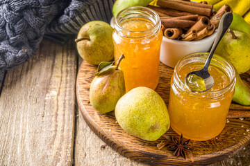 Homemade sweet and spicy pear jam. Different glass jars with pear jam, on wooden background with fresh pears and spices