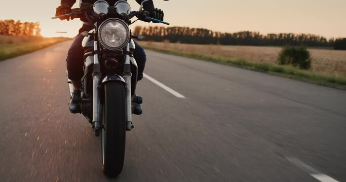 The motorbike rides on the highway at sunset, in the footage you can see the hands of the motorcyclist on the steering wheel