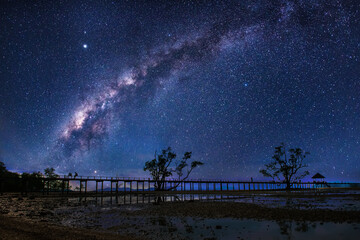 The Milky Way galaxy, on the bridge extending into the sea on Koh Mak, Long exposure photograph, with grain.Image contain certain grain or noise and soft focus.