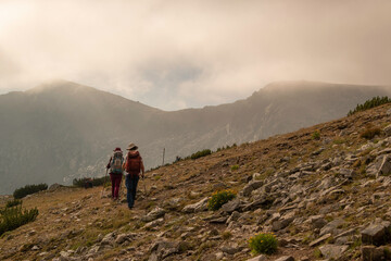 Obraz premium Group of hikers heading toward Pavlev peak in an early misty mourning. 