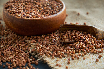 Buckwheat groats in a wooden bowl and vintage scoop. Close up on a black background. copy space for text