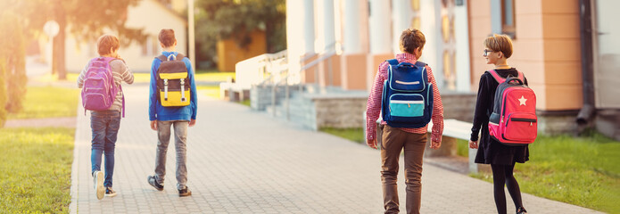 Children with rucksacks standing in the park near school
