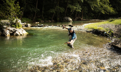 A fly fisherman fishing a trouts in mountain river