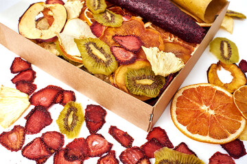 Scattered dried fruits and fruit pastille in open craft paper box