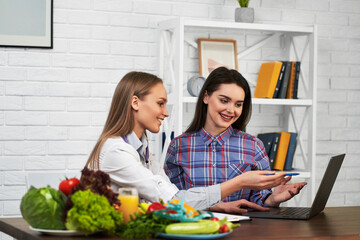 A smiling nutritionist advises a young patient woman on proper nutrition and dieting. Diet based on vegetables and fruits