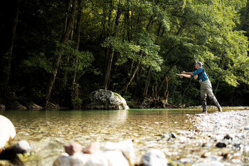 A fly fisherman fishing a trouts in mountain river