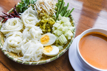 Thailand food vermicelli noodle boiled eggs and fresh vegetables on plate with curry soup bowl served wooden table - Thai rice noodles