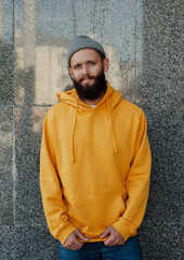 City portrait of handsome hipster guy with beard wearing yellow blank hoodie or sweatshirt with space for your logo or design. Mockup for print