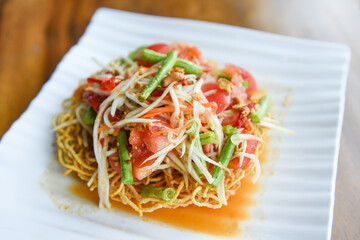 Papaya salad spicy on crispy noodles on white plate , Thai food with yardlong bean herbs and spices...