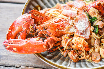 Grilled Lobster sausage ham vegetables and cheese spaghetti seafood on wooden table - Shellfish seafood plate with lobster dinner food cooked
