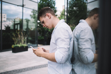 Fototapeta premium Focused male using smartphone in street