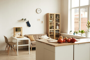 Horizontal no people shot of modern apartment room interior in daylight with ripe pumpkins lying on table, copy space