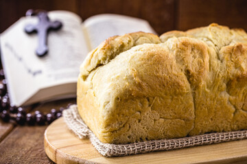 homemade bread made in the Easter and Eucharist period, called Christ bread, religious symbol, with Bible and crucifix in the background